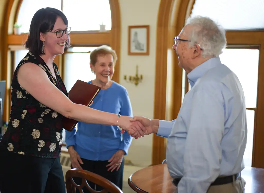 Lisa Kay Rosenthal greeting an older couple with a handshake in a bright meeting room during an estate planning consultation